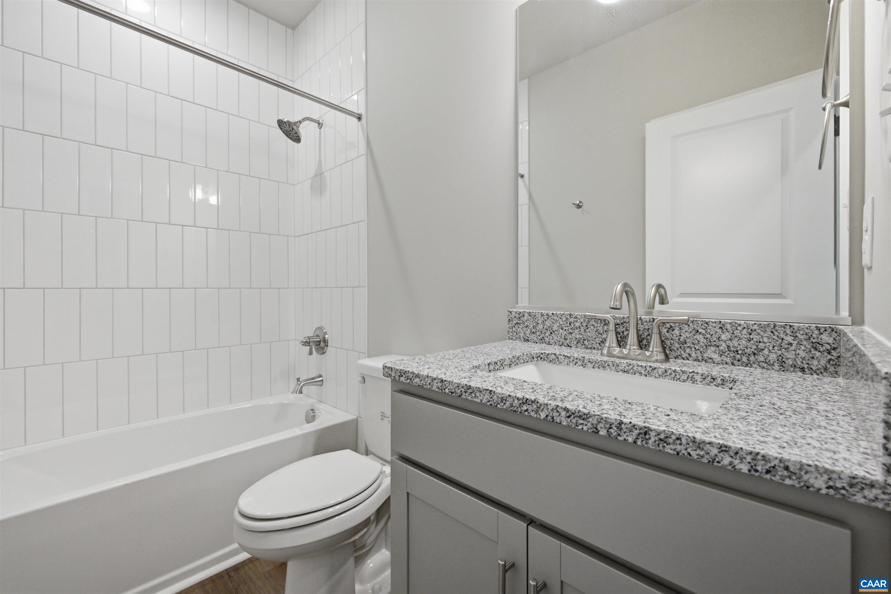 Hall Bath between bedroom 2 and 3, granite counter, tiled shower.  Photo of the for-sale home.
