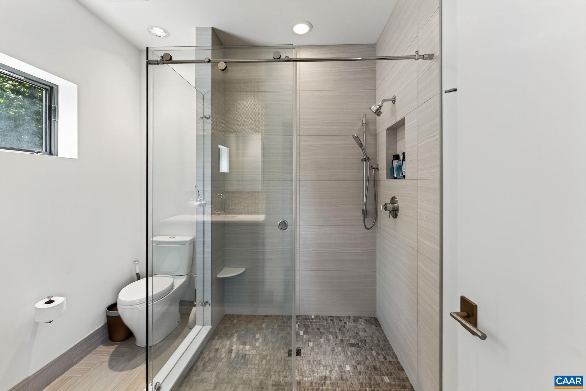 Fully tiled primary bathroom with walk-in shower. Fully tiled primary bathroom with walk-in shower.