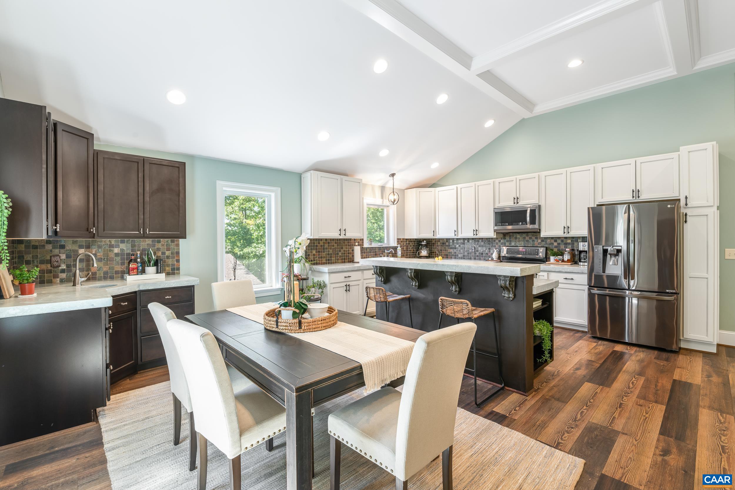 Dining area with dedicated wet bar, dark cabinetry, glass front storage and concrete countertops, opening to the kitchen Dining area with dedicated wet bar, dark cabinetry, glass front storage and concrete countertops, opening to the kitchen
