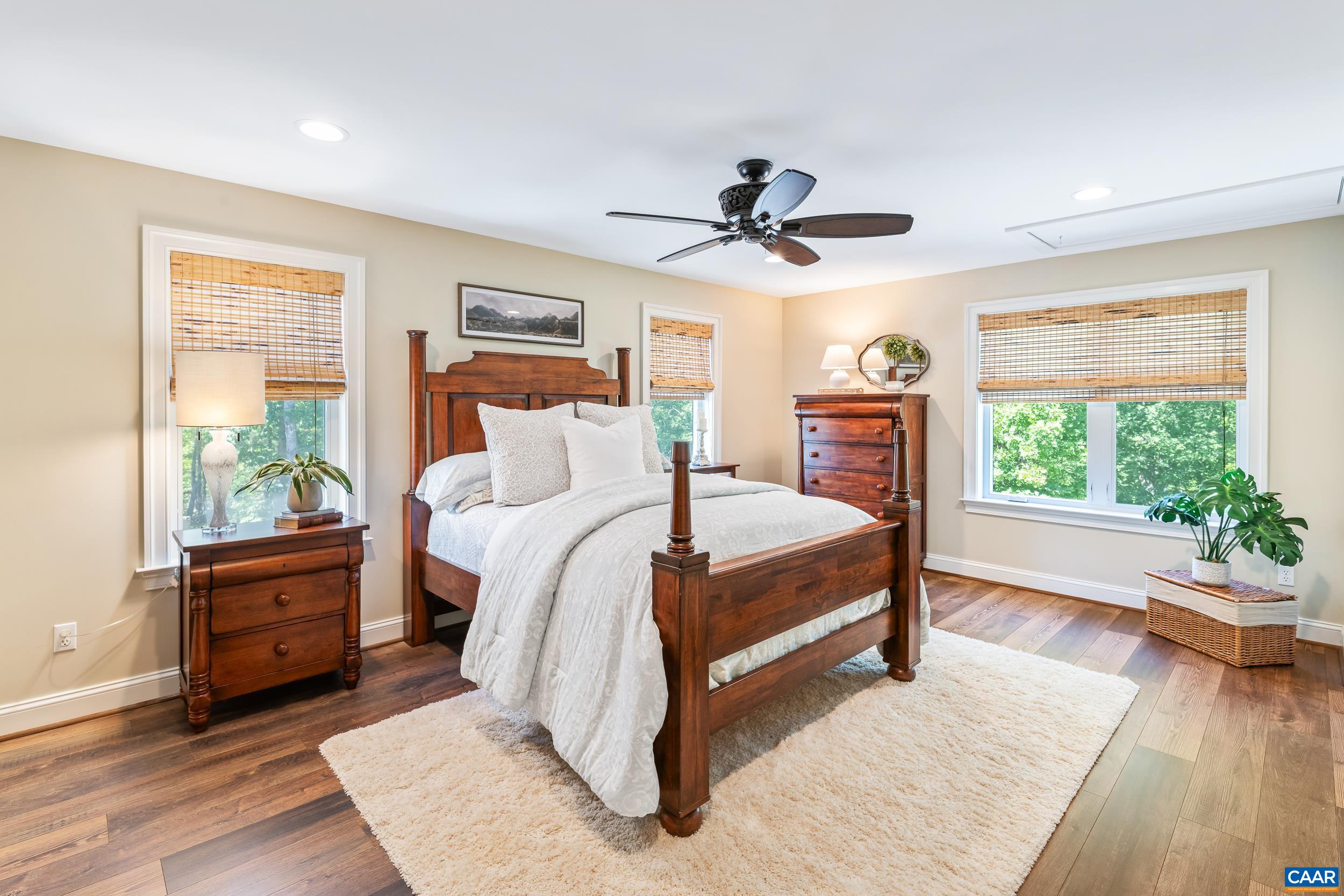 Spacious primary bedroom with hardwood floors, abundant natural light, custom blinds Spacious primary bedroom with hardwood floors, abundant natural light, custom blinds
