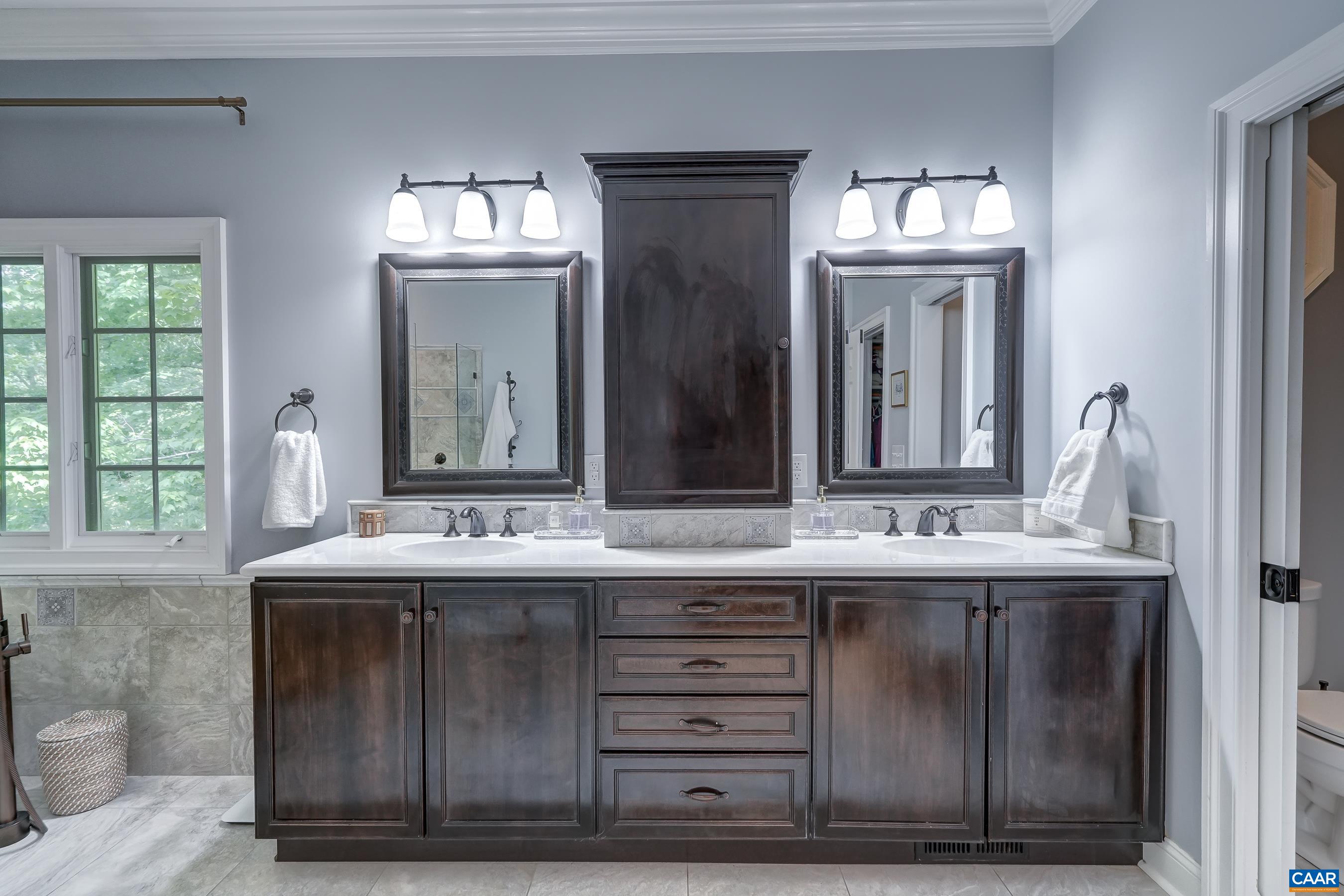 Spacious primary bathroom features dual sink vanity area with custom cabinetry. Spacious primary bathroom features dual sink vanity area with custom cabinetry.