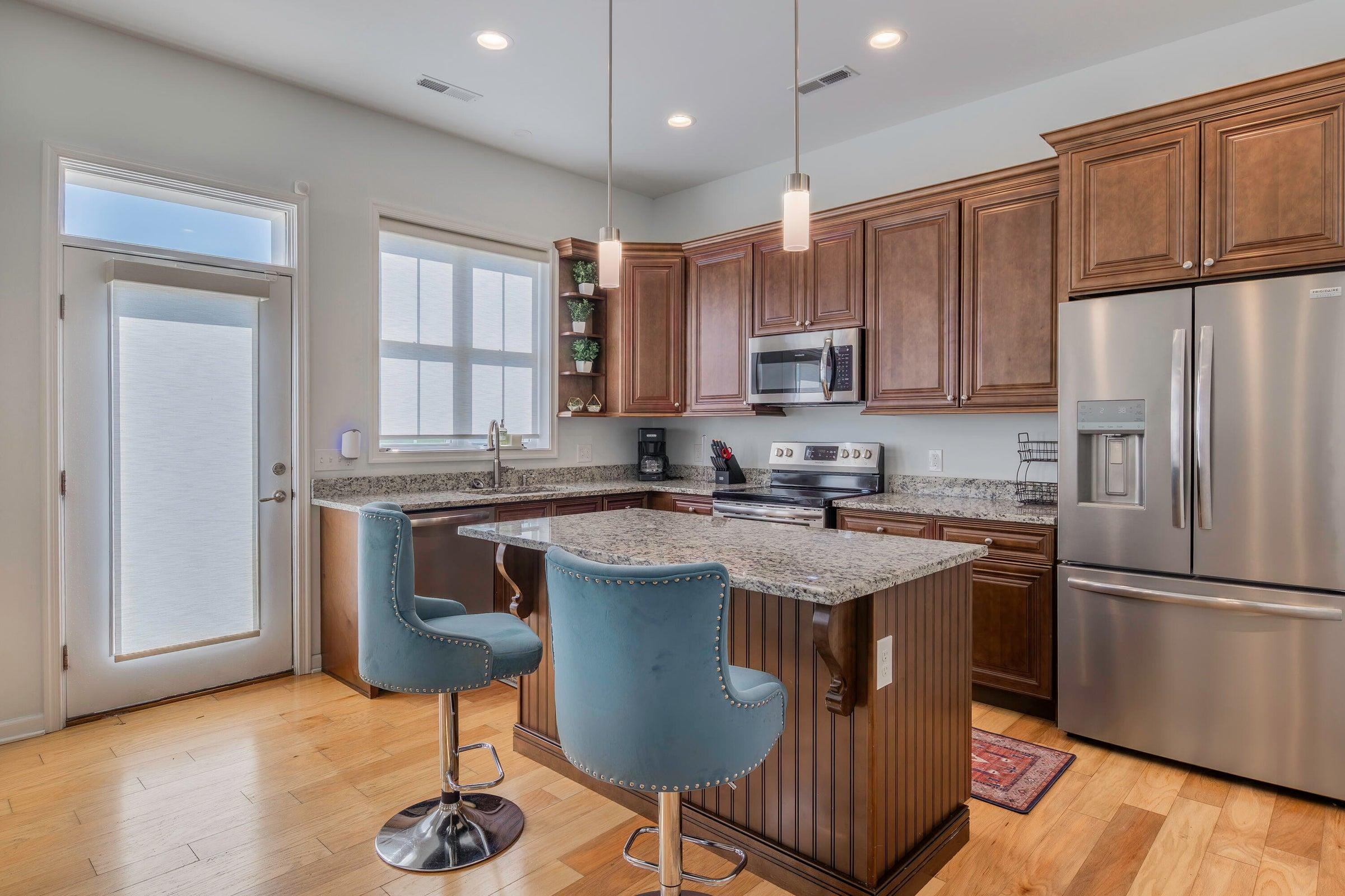 Open kitchen with granite countertops, dark wood cabinetry, stainless steel appliances, and a center island.