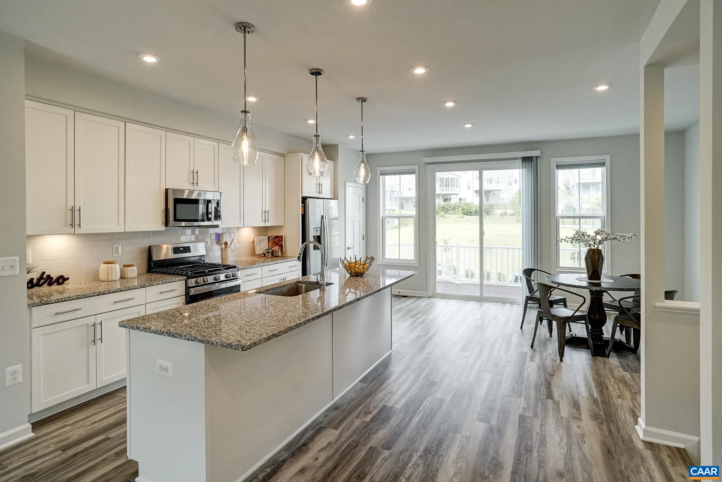 Practical and polished kitchen features granite counters, white cabinets, pendant lights and stainless appliances.