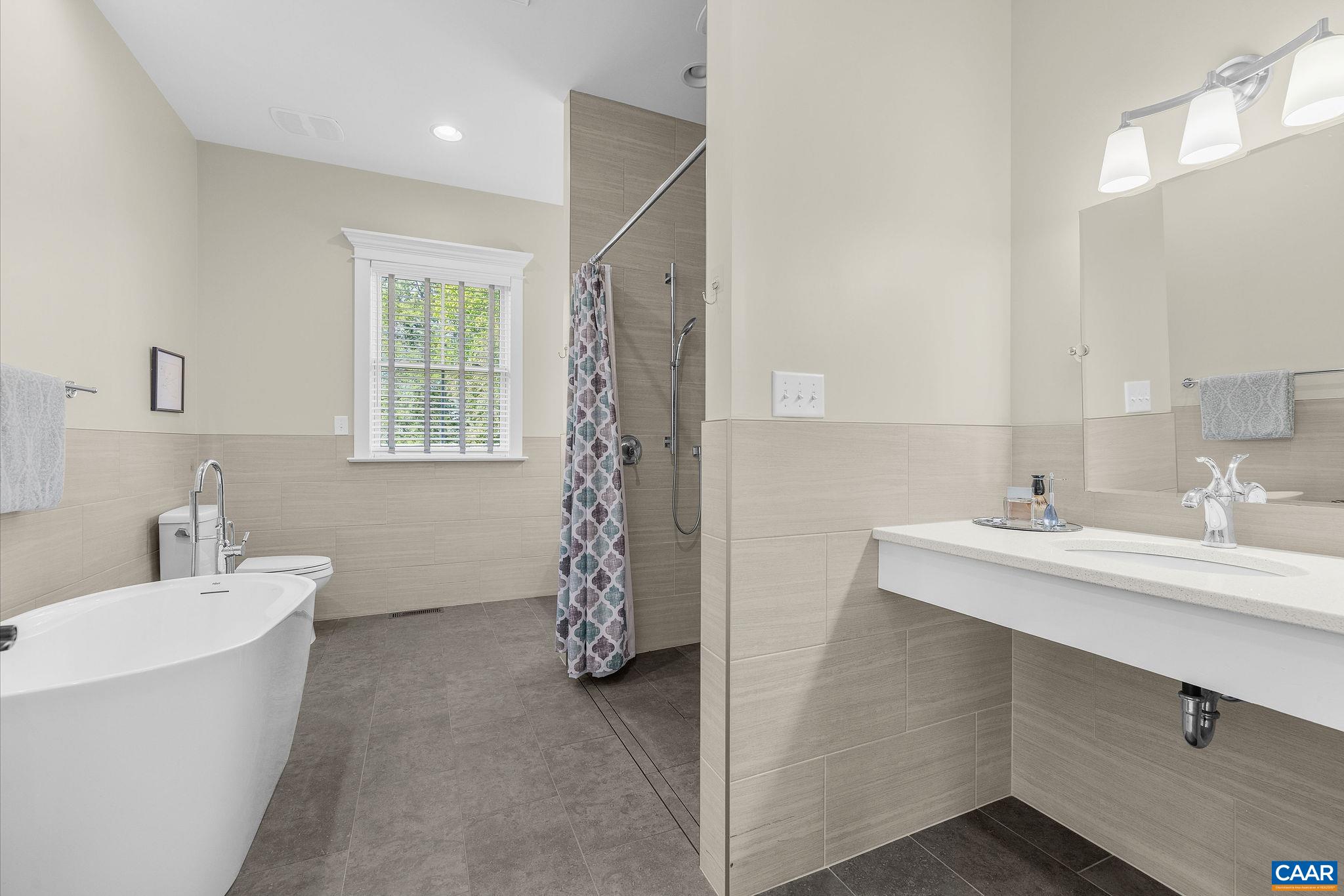 Handicapped accessible primary bathroom with soaking tub and zero entry shower