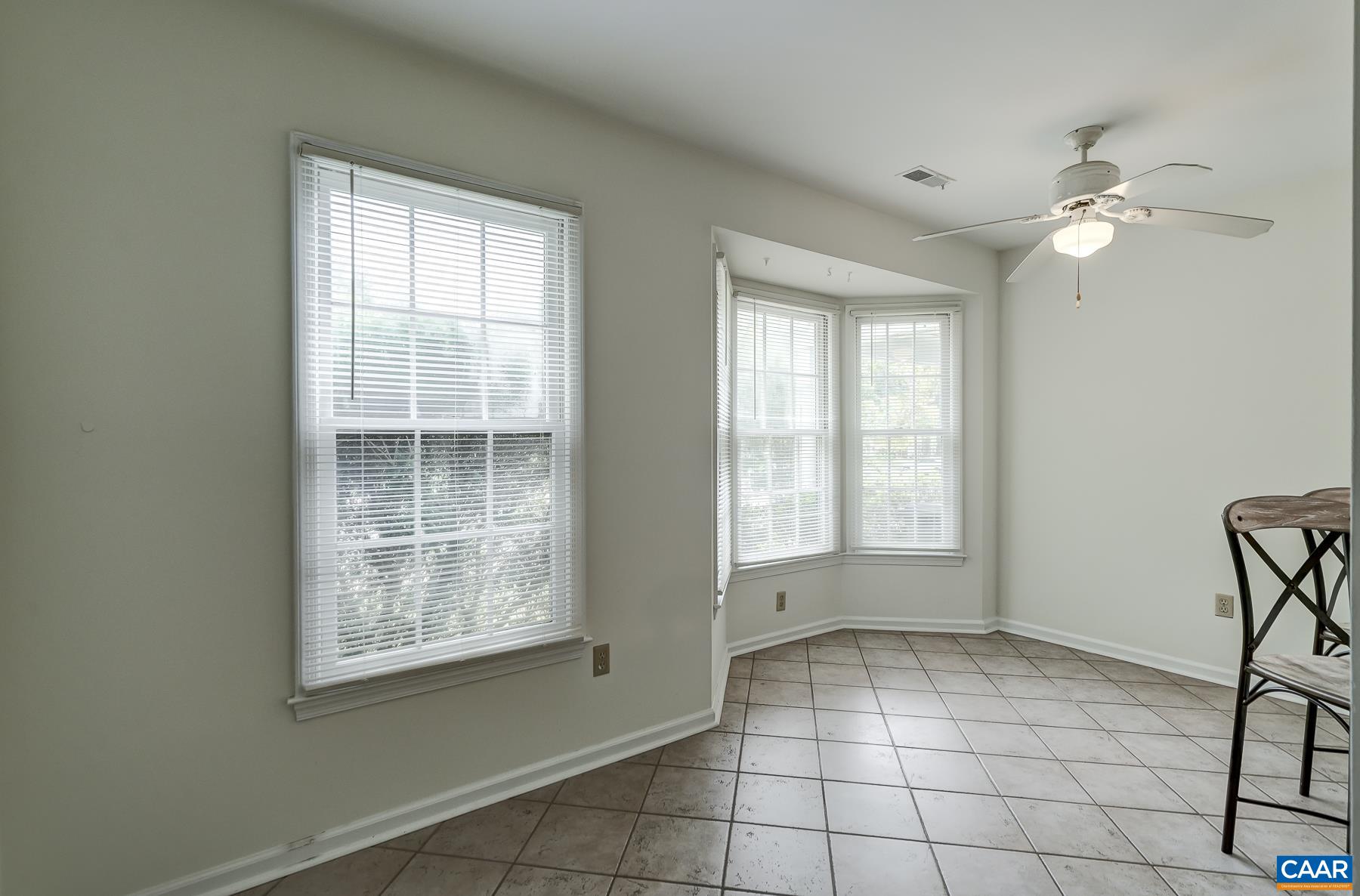 Eat-in breakfast nook with bay window and ceiling fan.