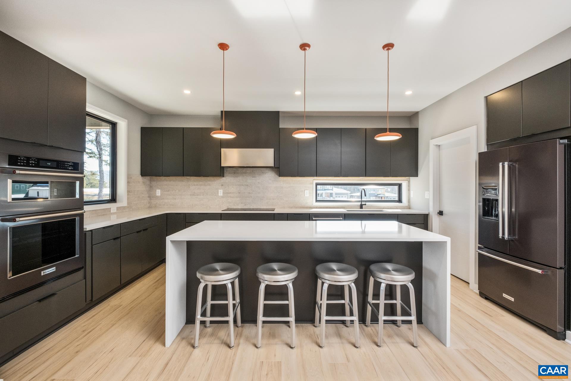 Modern, open kitchen features large quartz island with waterfall sides.