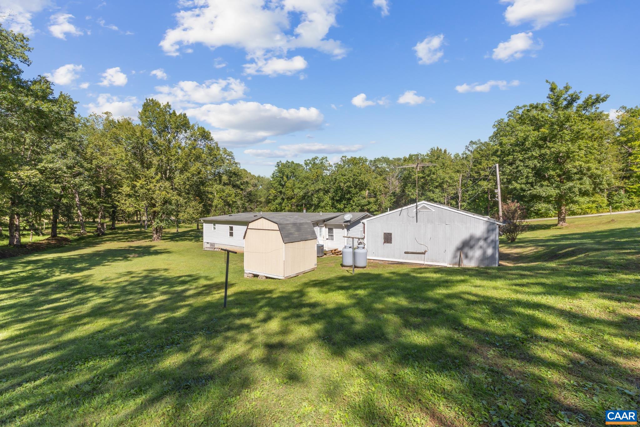A peaceful rear view of the home featuring a spacious backyard, outdoor shed, and a detached 2-car garage equipped with a full bath! Nestled on 6.73 total acres, this versatile property offers endless room for work, storage, and relaxation. A peaceful rear view of the home featuring a spacious backyard, outdoor shed, and a detached 2-car garage equipped with a full bath! Nestled on 6.73 total acres, this versatile property offers endless room for work, storage, and relaxation.