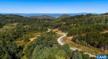 The Reserve's private road through the hardwoods, with the Blue Ridge beyond.