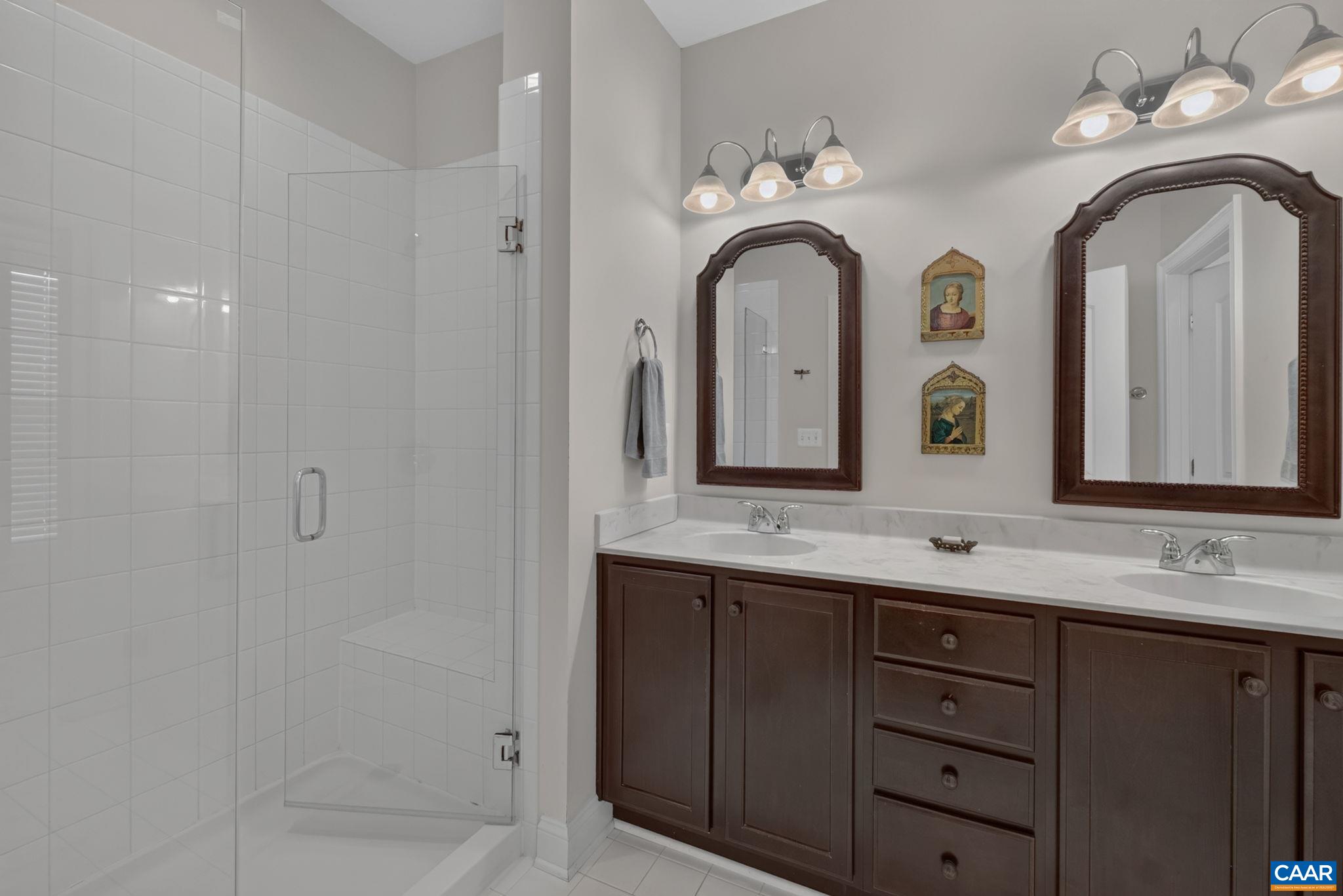 Fully tiled primary bathroom with with double sink vanity. Fully tiled primary bathroom with with double sink vanity.