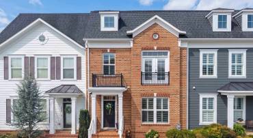 The front view of the townhouse highlights the fully brick exterior, covered front porch space, landscaping, and much more!