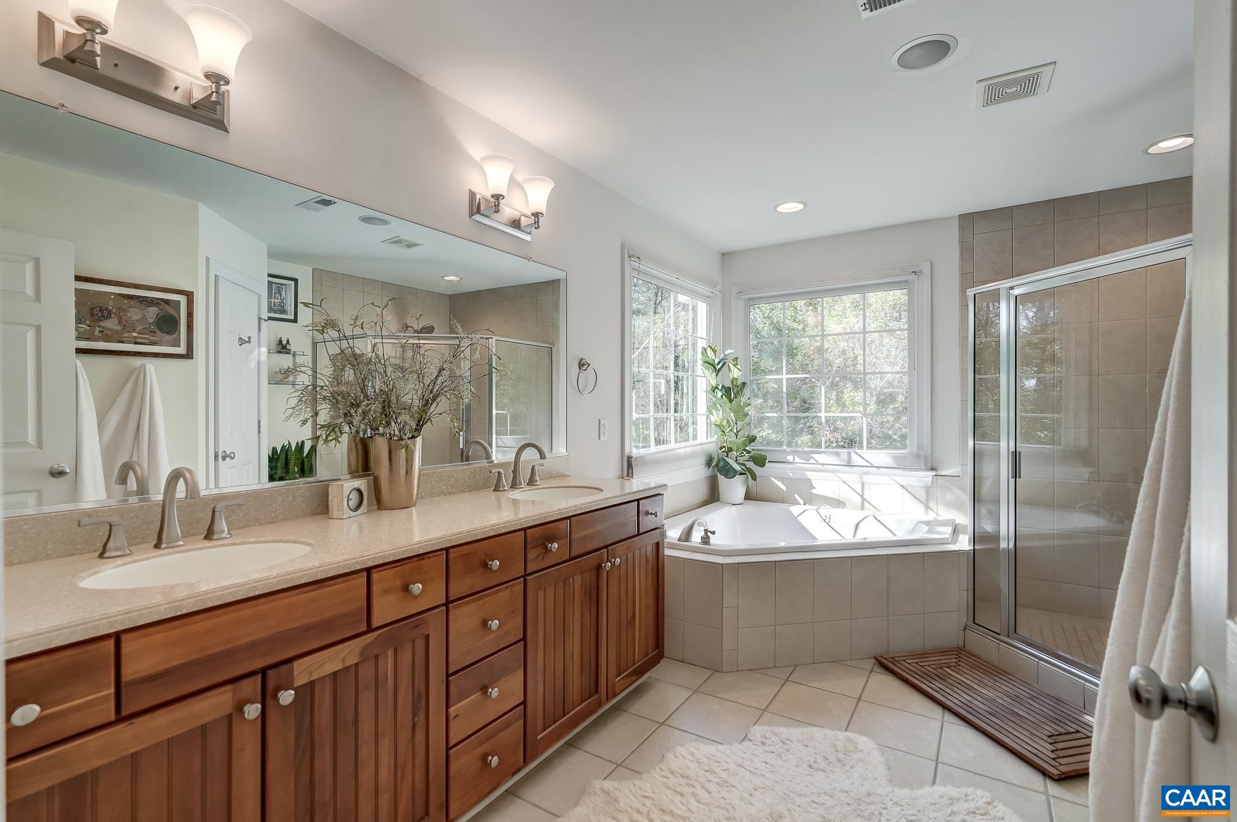 Primary bathroom with jetted corner tub and separate shower, plus double sink vanity with solid surface countertop. Primary bathroom with jetted corner tub and separate shower, plus double sink vanity with solid surface countertop.