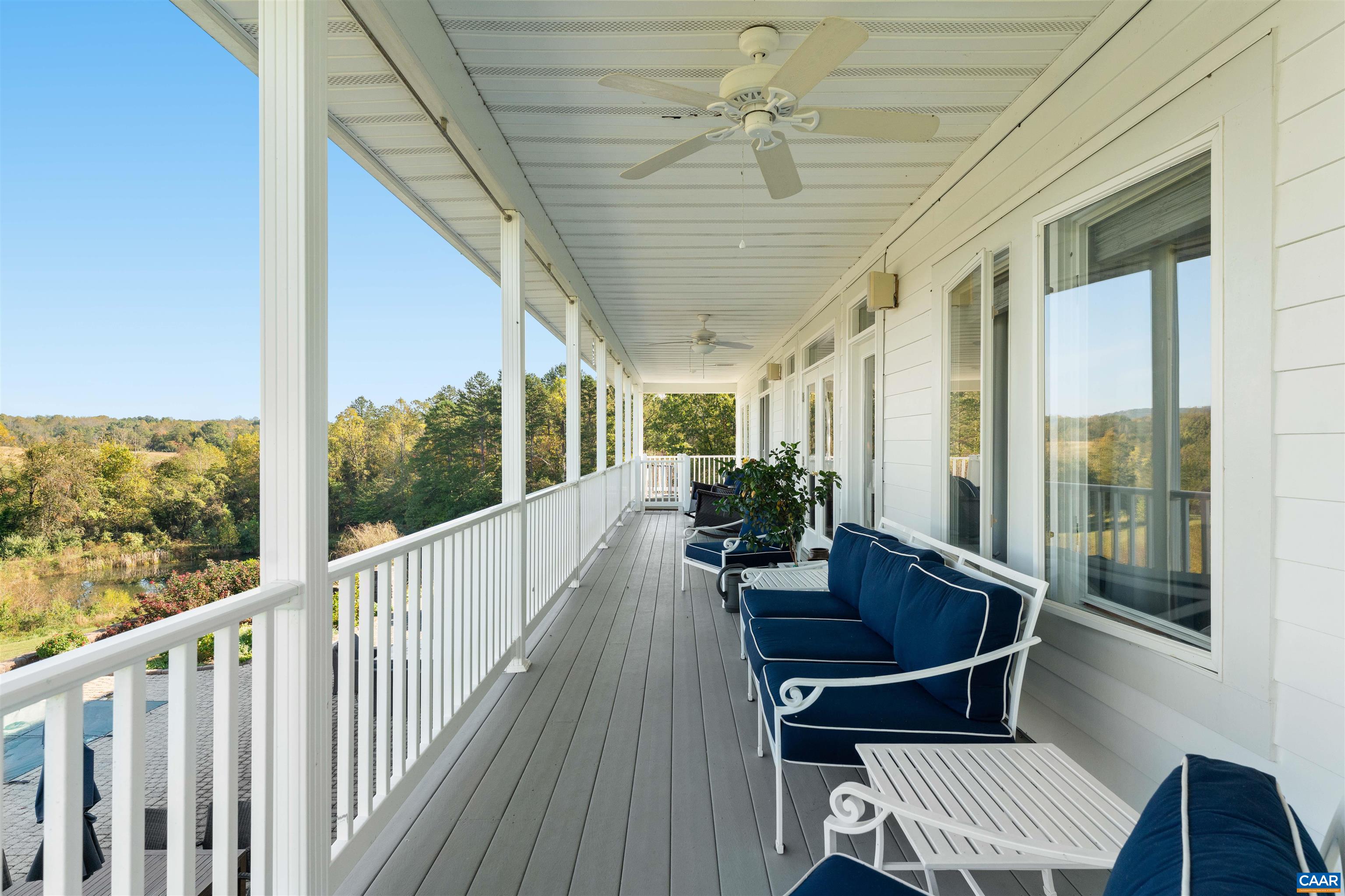 The covered porch extends the length of the house, with ceiling fans and views over the fields and woodland. The covered porch extends the length of the house, with ceiling fans and views over the fields and woodland.