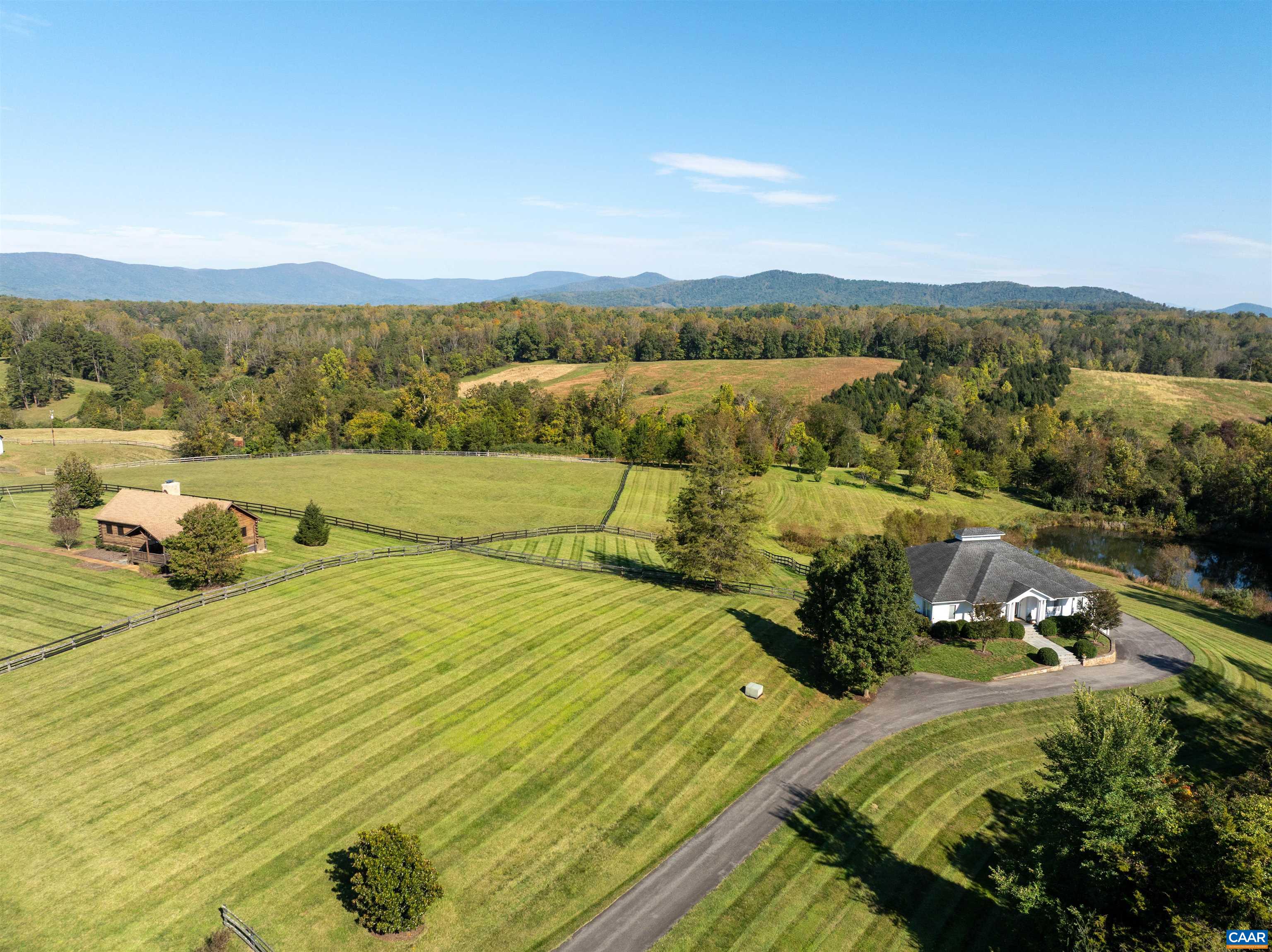 The main residence and the log cabin from above, each within its own fenced pasture, with the Blue Ridge on the horizon. The main residence and the log cabin from above, each within its own fenced pasture, with the Blue Ridge on the horizon.
