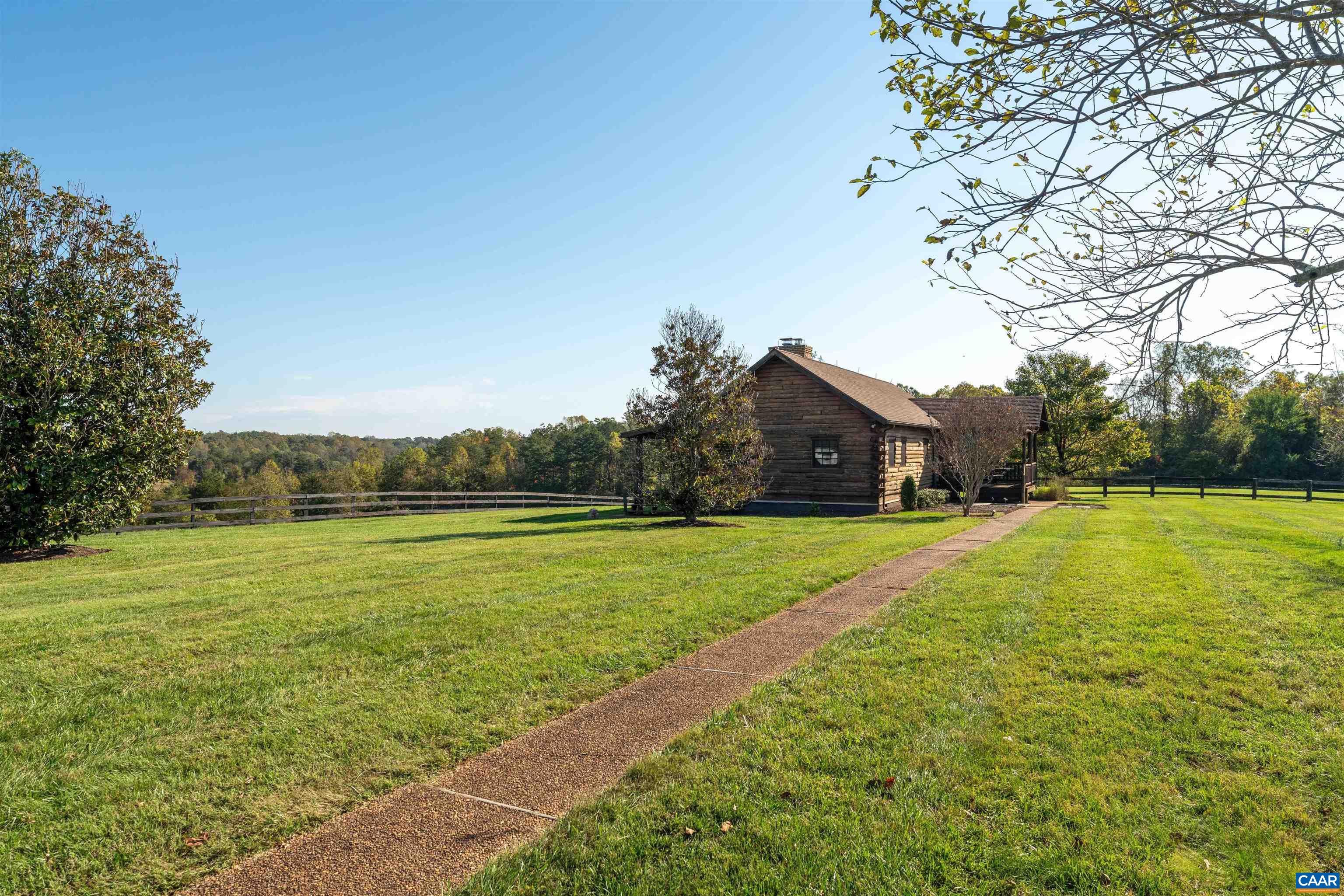 The cabin sits apart from the main residence across open lawn, reached by a gravel path. The cabin sits apart from the main residence across open lawn, reached by a gravel path.