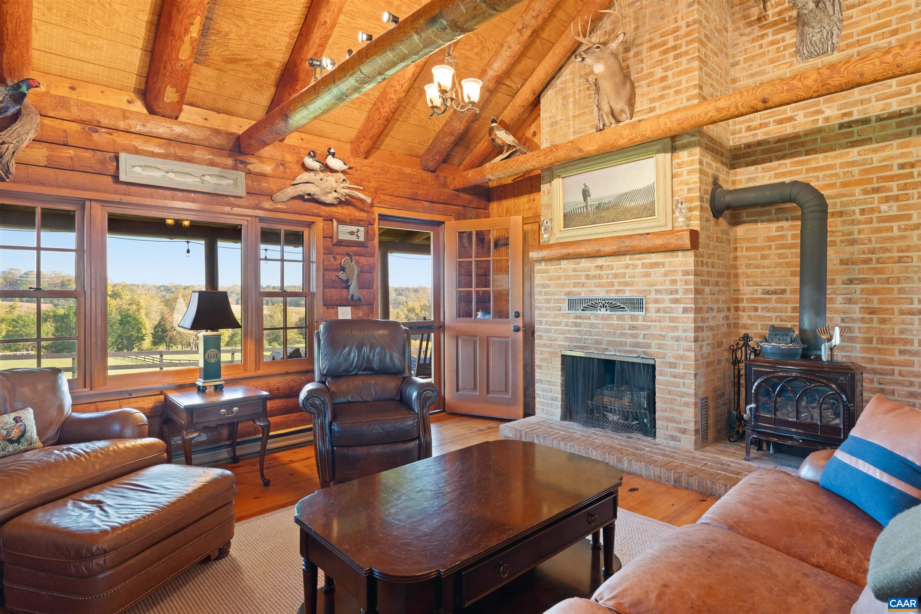 Cabin living room with exposed beams, brick fireplace, high-efficiency Jotul wood stove and windows to the pasture. Cabin living room with exposed beams, brick fireplace, high-efficiency Jotul wood stove and windows to the pasture.