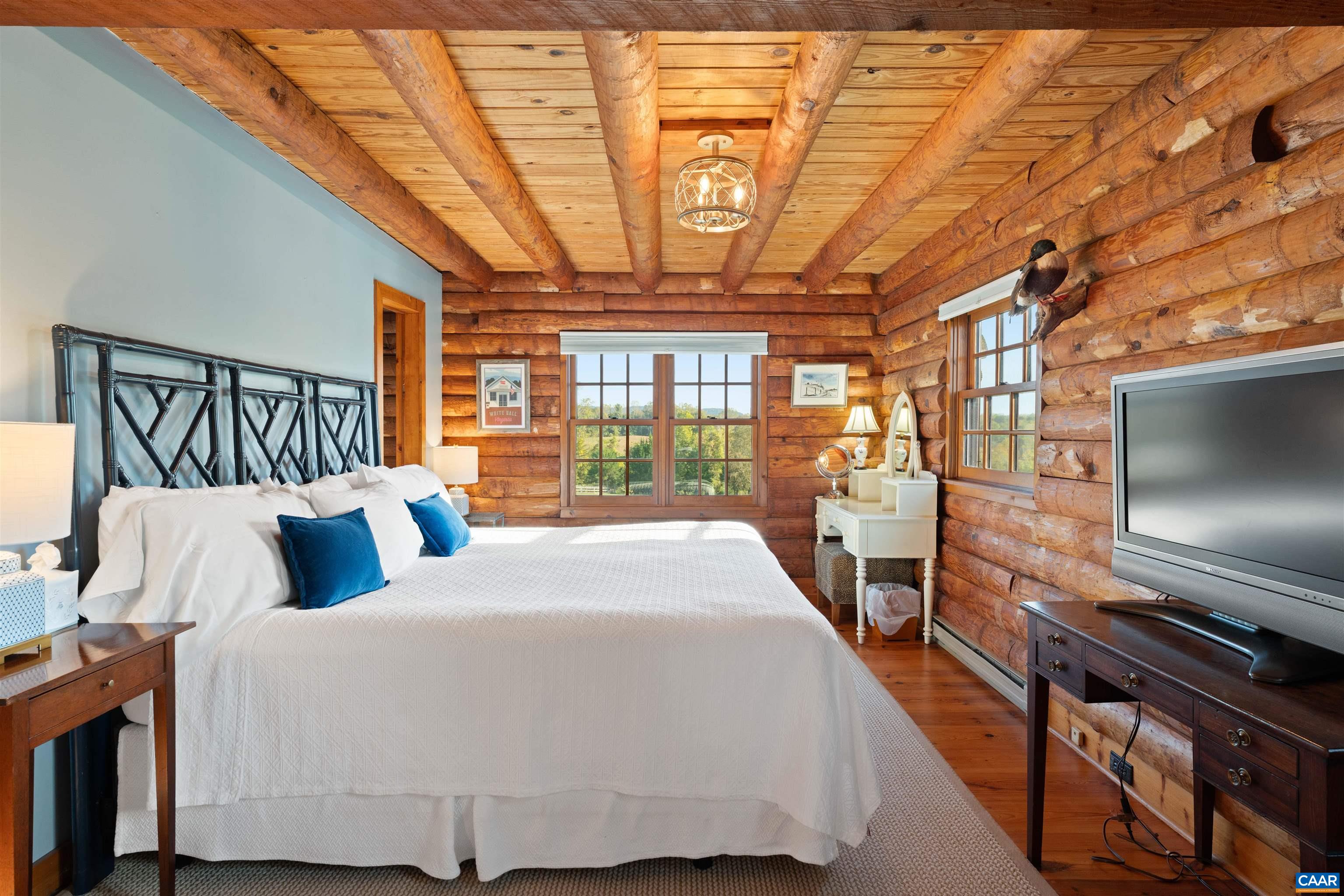 Cabin bedroom with log walls and beamed ceiling. Cabin bedroom with log walls and beamed ceiling.