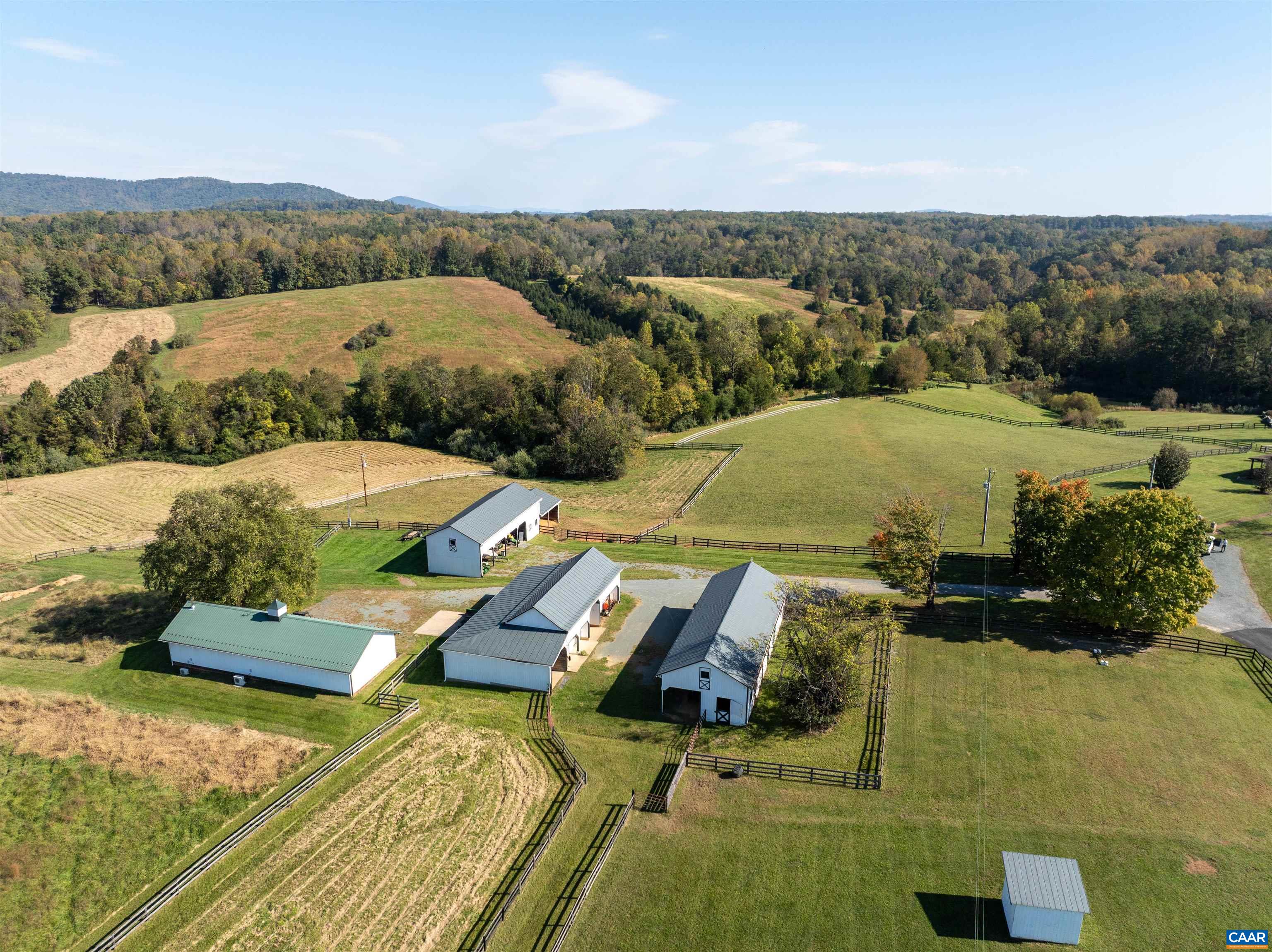 Aerial view of the barn complex among the paddocks: the original six-stall barn with office and tack room, the four-bay barn built in 2013, and the equipment barn. Aerial view of the barn complex among the paddocks: the original six-stall barn with office and tack room, the four-bay barn built in 2013, and the equipment barn.