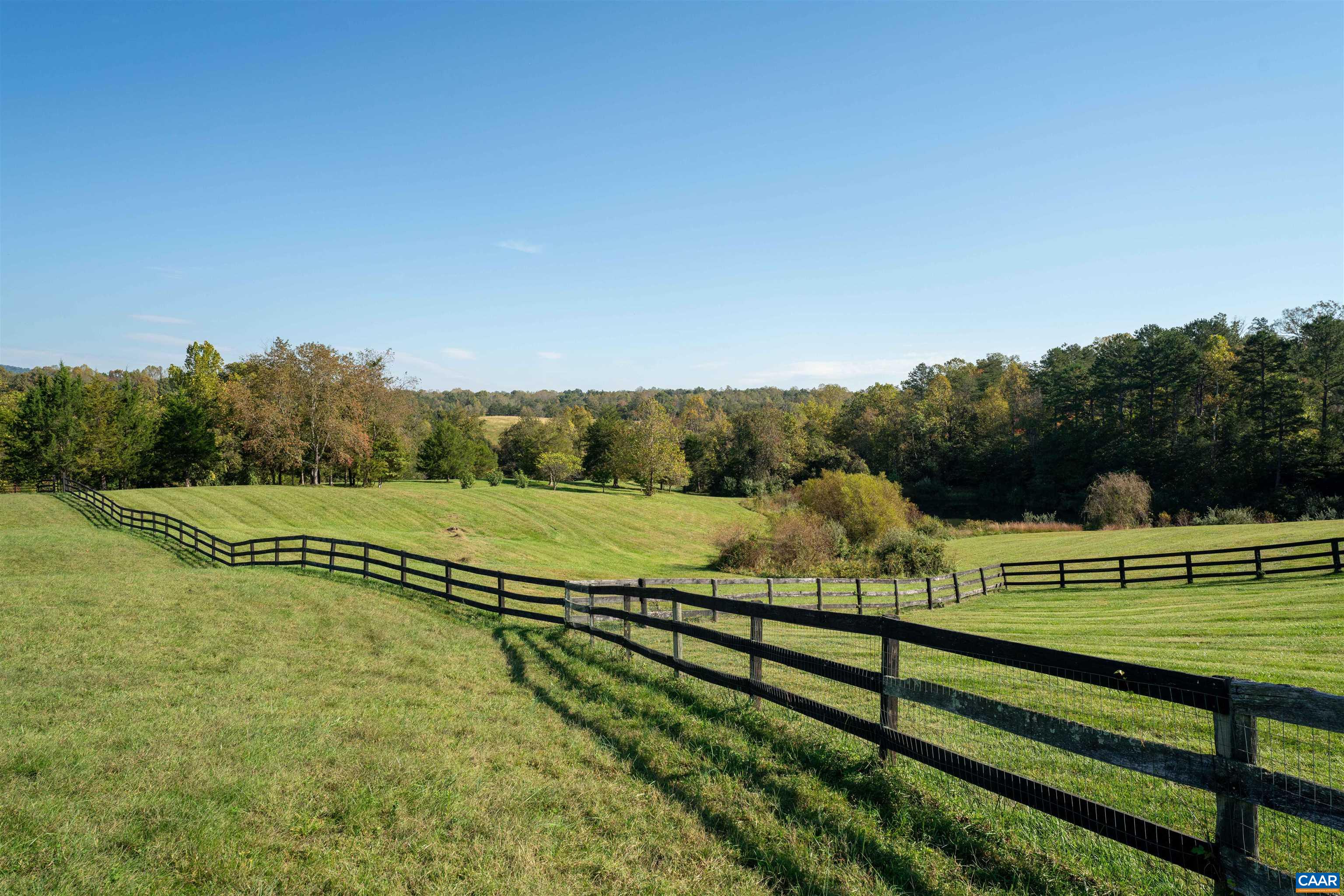 Board fencing along the pasture, with hardwoods and open fields beyond. Board fencing along the pasture, with hardwoods and open fields beyond.