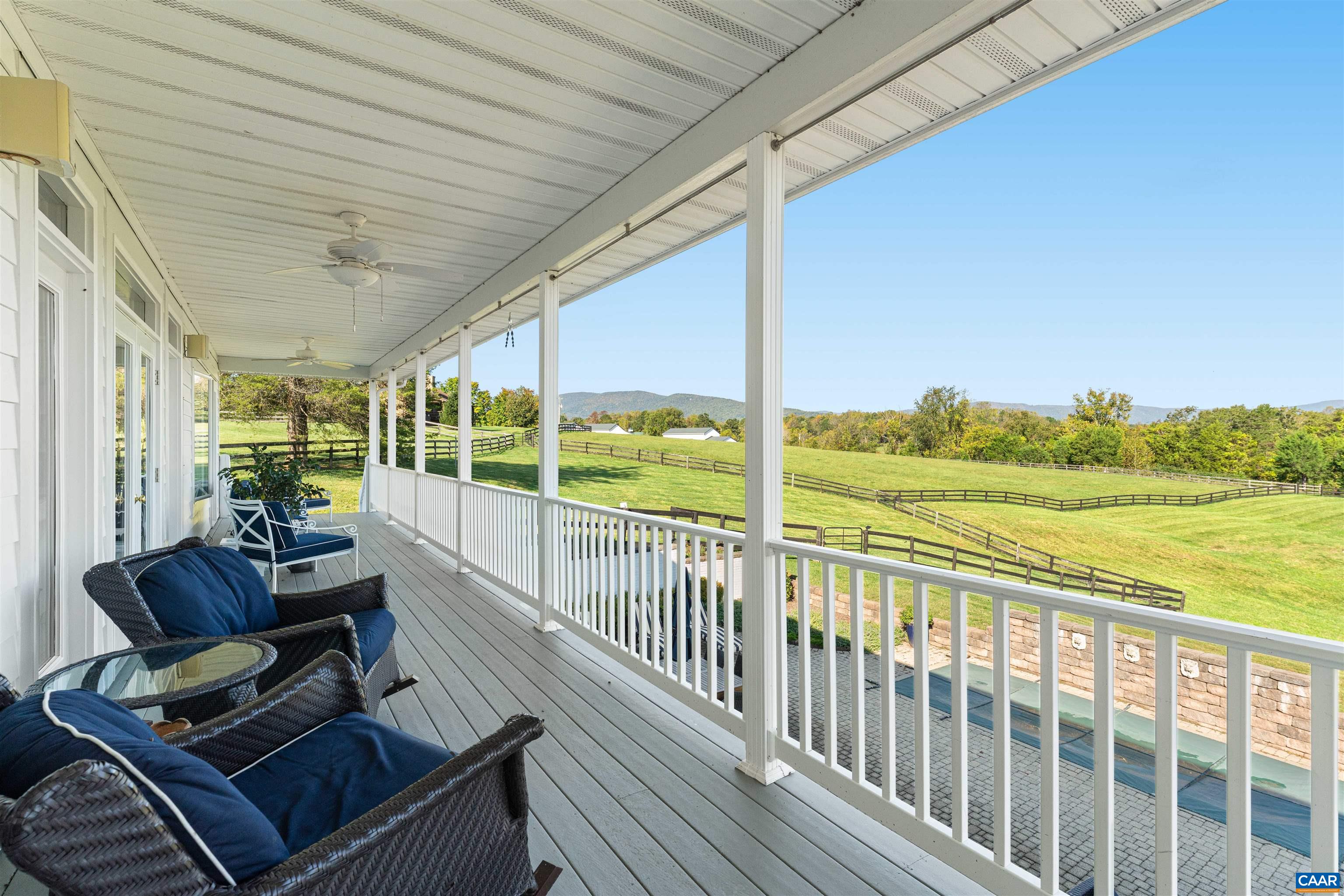 The covered porch runs along the back of the house above the board-fenced paddocks, with views across the fields to the mountains. The covered porch runs along the back of the house above the board-fenced paddocks, with views across the fields to the mountains.