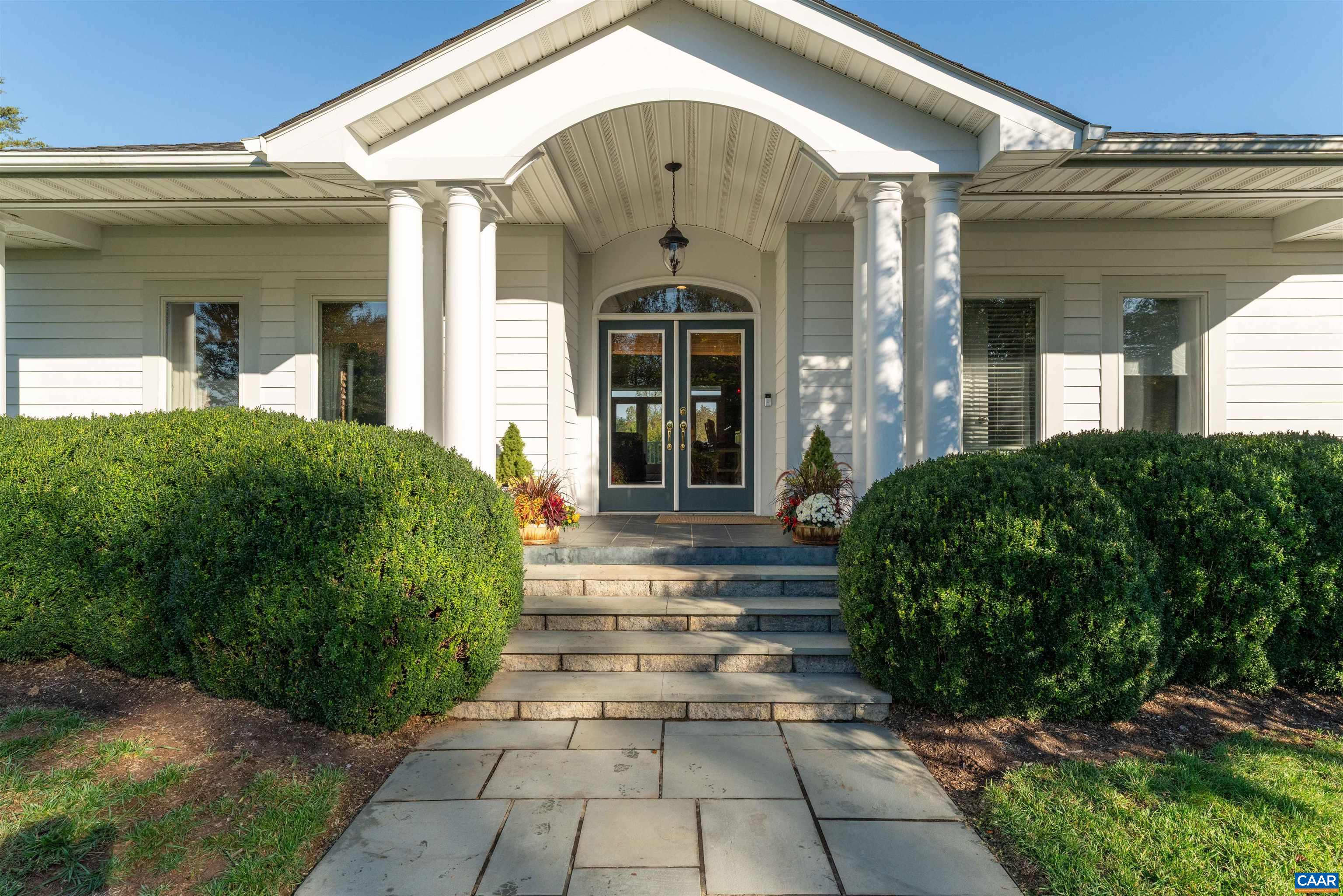 Columned entry portico with double doors, flagstone steps and mature plantings. Columned entry portico with double doors, flagstone steps and mature plantings.