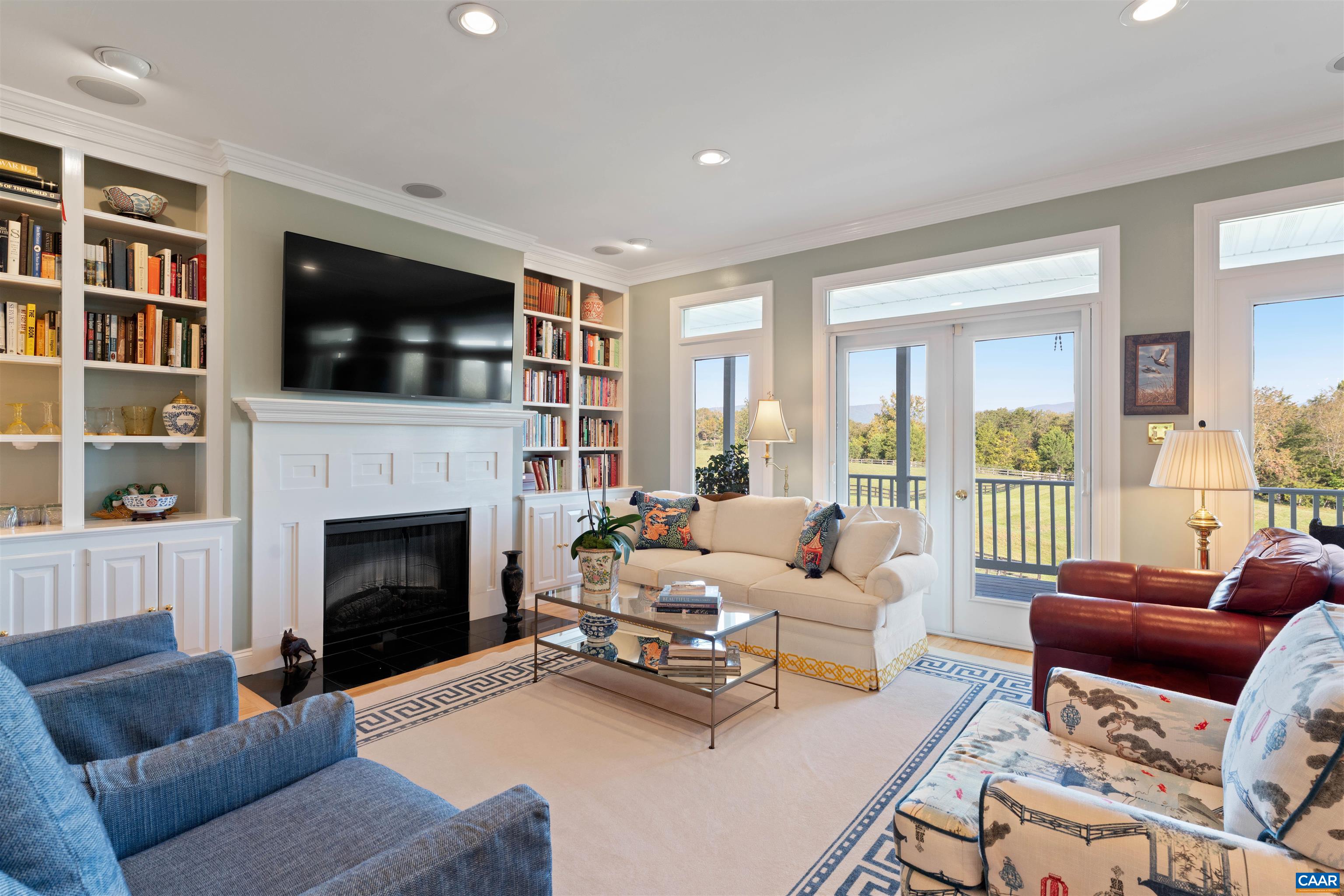 Living room with fireplace and built-in bookcases. French doors open to the covered porch and the view. Living room with fireplace and built-in bookcases. French doors open to the covered porch and the view.