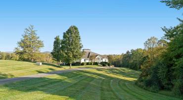 The private paved drive climbs through open pasture to the residence, set high on the rise.