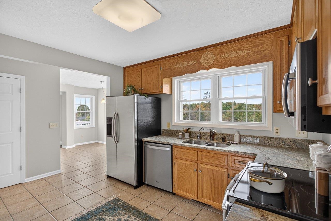 The kitchen features tile floors, granite countertops, stainless steel appliances, a pantry, and plenty of natural light.