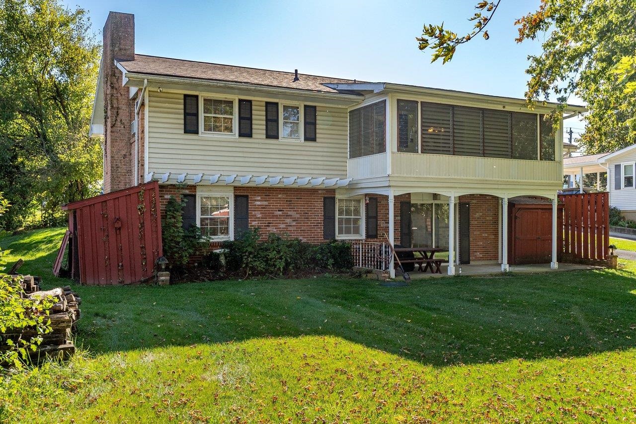 The back of the home features an enclosed sun porch and a concrete patio, providing extra space to relax and enjoy the large backyard.