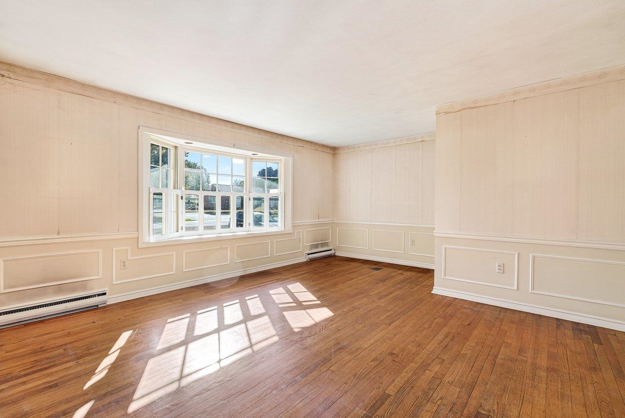 The spacious living room features hardwood floors and a large window that fills the space with natural light.