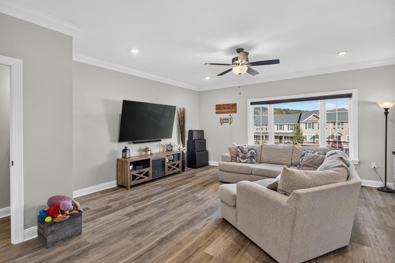 The spacious living room features oversized windows, 9-foot ceilings, recessed lighting, LVP floors, and a ceiling fan.