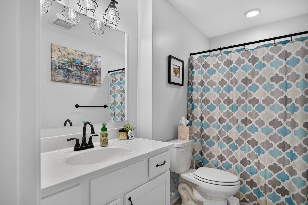 The second-floor bath features a tub/shower combination, and white vanity with a cultured marble sink top and stylish lighting.
