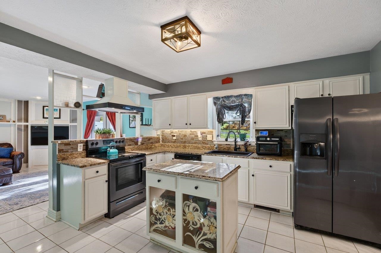 The kitchen features sleek tile flooring, granite countertops, an island, and stainless steel appliances. The bright, airy space opens to the family room, creating a convenient layout for everyday living.