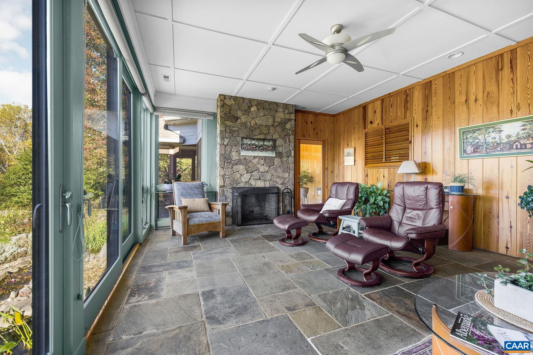 Four-seasons sunroom with wood-burning stone fireplace, heart pine wall cladding & blue stone floors