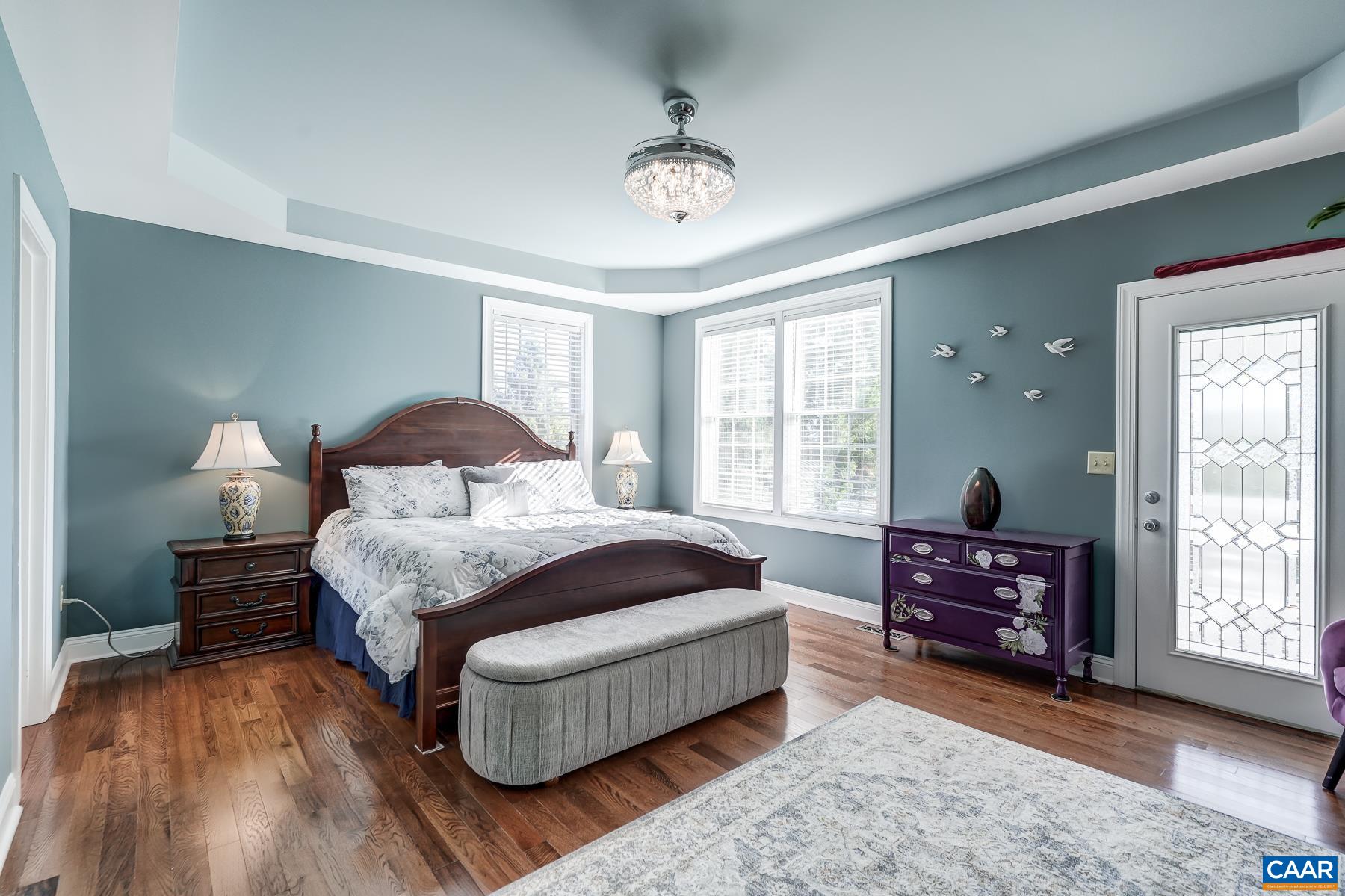 Main level primary suite features tray ceiling and new hardwood floors, plus door leading to deck. Main level primary suite features tray ceiling and new hardwood floors, plus door leading to deck.